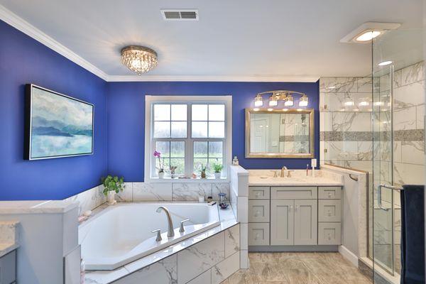 Master bathroom remodel with corner bathtub & marble lined tiles