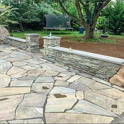 Stacked stone seating wall with accent bolders as pillars