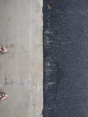 White horizontal machinery gouge/scratch in garage apron + streaky asphalt.