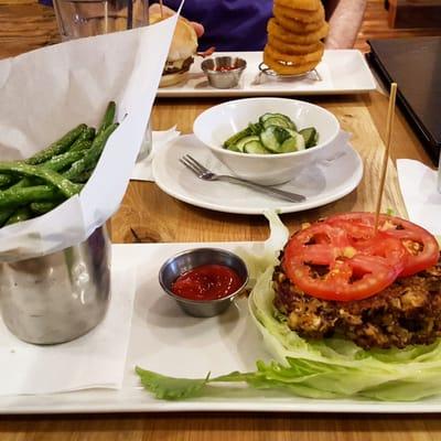 Veggie burger in the grass with green bean fries.