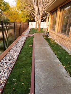 Iron fencing, sod, concrete path, block retaining walls, composite edging and rock installation