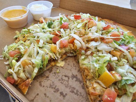 Taco Pizza - a 10" crust slathered with refried beans, seasoned ground beef, tortilla strips, cheese, taco sauce, tomatoes & lettuce