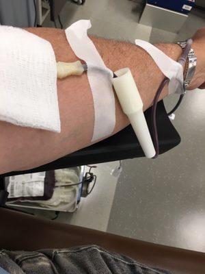 Donating blood which is collected in the bag at the bottom.