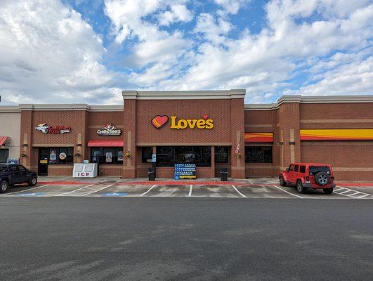 Outside the convenience store. Storefront. Hardee's, Godfather's Pizza Express, and Chester's attached and on-site. 1.0x zoom. Pixel 7.