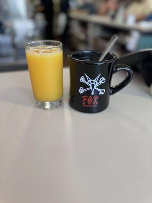 A very cool coffee cup, and some orange juice.