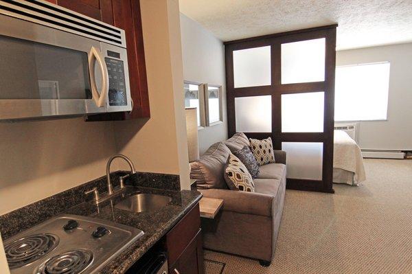 Kitchenette with stove top, mini-fridge and microwave oven.