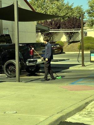 Half assed job "washing" vehicles & then drags his brush all over the ground while he waits.