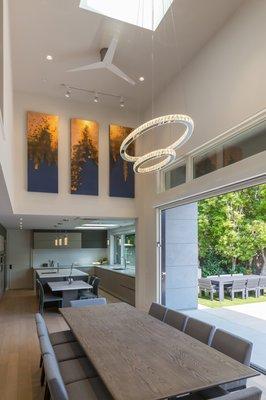 An indoor/outdoor dining experience, with a high ceiling, an open kitchen concept, and a view to the backyard.