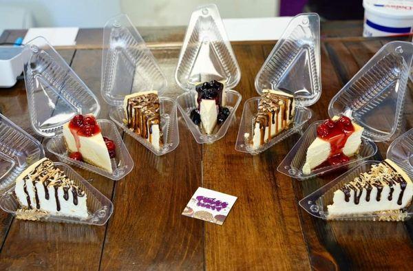 Assorted new york style cheesecake slices: chocolate coconut, cherry, turtle, blueberry.