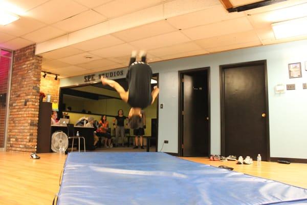 One of our B-boys working on his front tuck (front flip) on the mats... He's got it now!