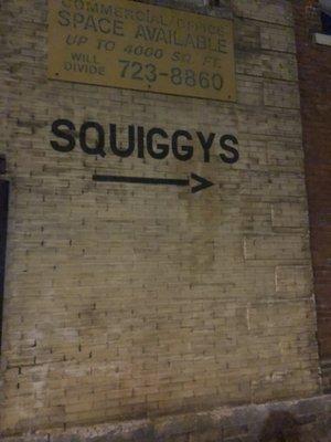 The entrance to Squiggy's is on the side of the building, towards the back. Follow the arrow!