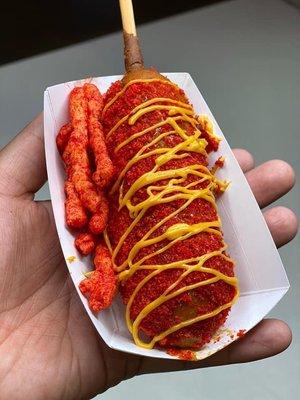 Corn dog topped with hot Cheetos