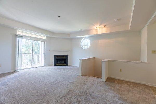 Spacious living room with gas fireplace and glass sliders to balcony