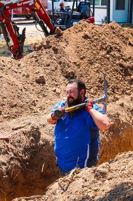 Our crew carefully digging a trench by hand for a plumbing installation, ensuring precision and care every step of the way.