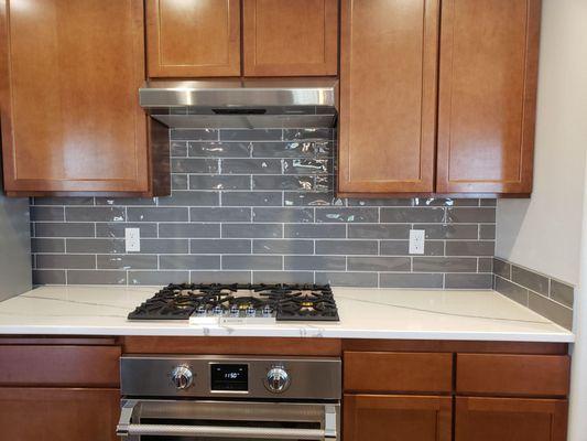 Full-height tile backsplash installation, set and grout, with schluter trim. White marble-like quartz countertop installation.