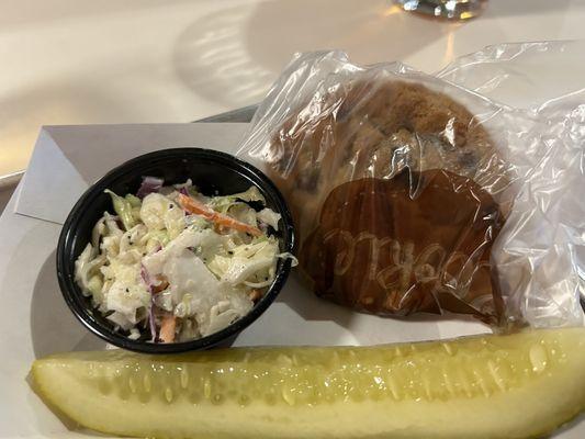 Sides coleslaw, pickle, and chocolate chip cookie