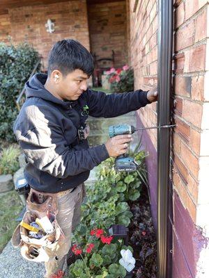 Sergio securing the final downspout to the exterior of the home