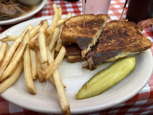 Chicken breast with bacon on rye bread with French fries and dill pickle