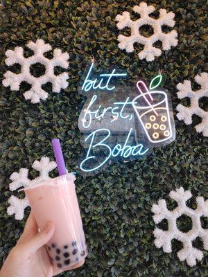 Rose milk tea taken in front of their lighted wall