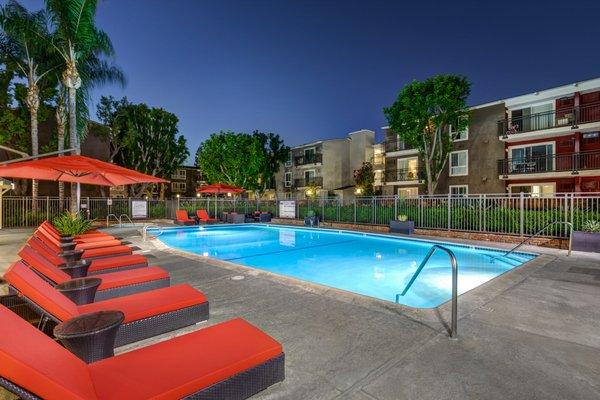 Twilight photo of pool with lounge furniture.