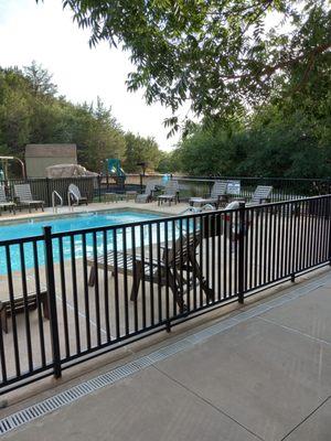 Pool and a playground behind the pool surrounded by trees. A lovely setting.