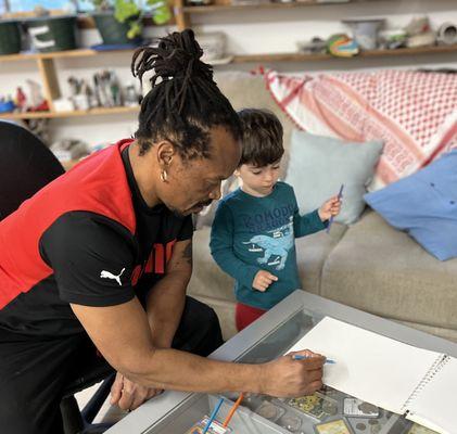 Ian teaches a child how to draw