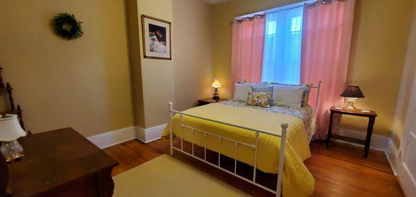 The colorful Folger guest room has a metal queen bed, Roku tv, ceiling fan, private bathroom, and sitting room for additional space.