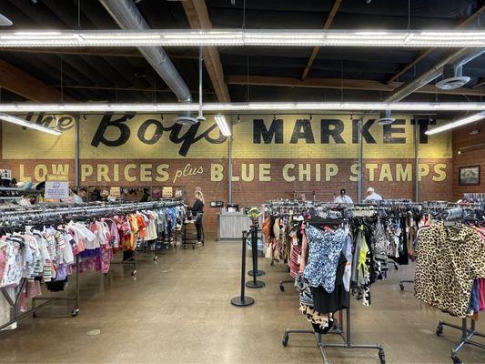 Immaculate clothing racks with painted signage on brick wall.