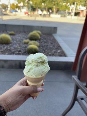 Single scoop pistachio ice cream on a plain cone