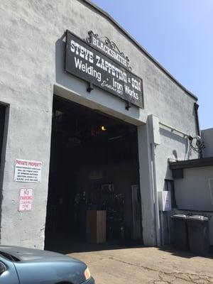 Front entrance to welding shop; cross street is A Street.