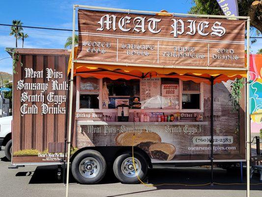 One of many food catering trucks offering substantial meals and snacks.  Patio tables with umbrellas are set up.