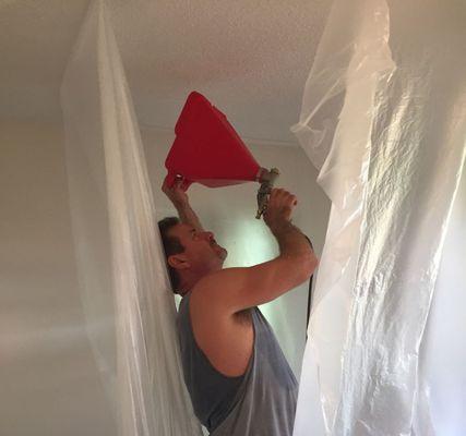 Spraying texture on a customer's ceiling over a repair to match existing texture throughout