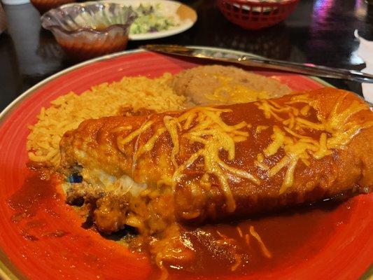 Chimichanga with red sauce and a side of rice and beans.