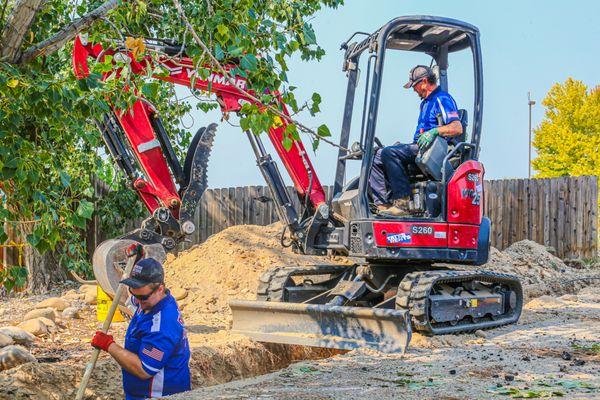 An excavator digging a trench for a sewer line, handled by our expert team at Plumbing Solutions of Idaho.