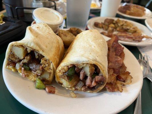 Mexican breakfast burrito with salsa and sour cream and a side of bacon