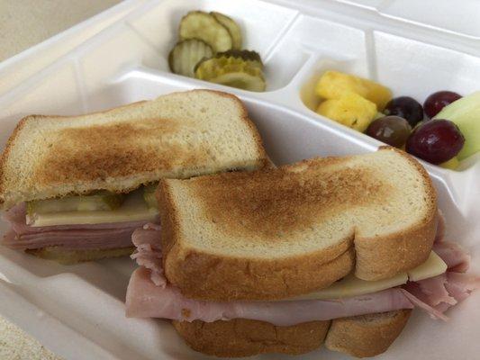 Ham and Swiss sandwich with pickles and fresh fruit