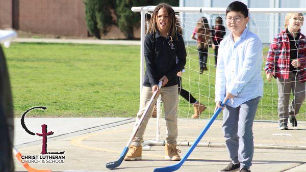 Students playing hockey in the playground area.