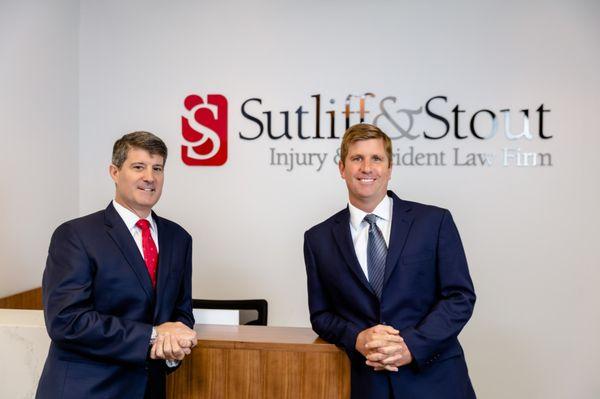 Founds of Sutliff & Stout, Graham Sutliff & Hank Stout pose for a photo at the reception desk of the firm.