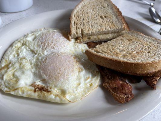 Two eggs over easy with bacon and rye toast