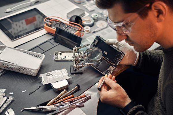 Tech fixing a phone logic board.