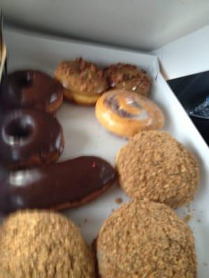 An assortment of maple bacon, round chocolate, long john, cinnamon roll and Persians.