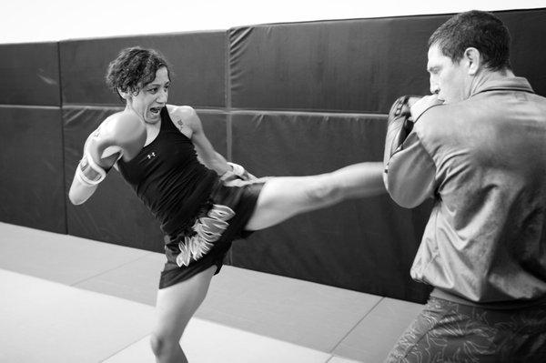 Coach, Mac Danzig holing kick pads for Angela in preparation for a fight.