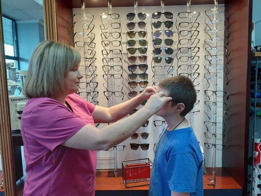 Our experienced optician using her many years of experience to find the perfect frame for each of our patients