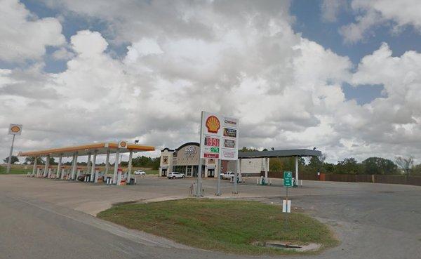 Storefront showing Shell gas pumps plus fast food vendor signs