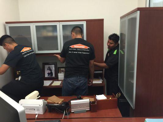 Our team at work moving out contents out of an office to prepare for drying out a large office space in order to not get dust on items.