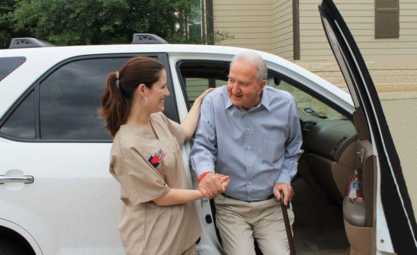 Caring Senior Service caregiver helping a client get our of a car