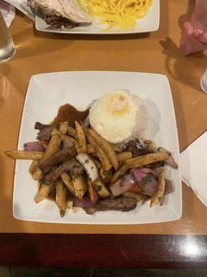 Lomo Saltado, fried egg on rice, fries, onion, tomato, steak, soy sauce