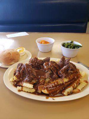 Pot roast over fries with veggies.