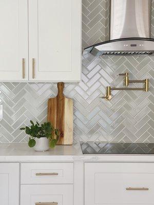 Herringbone backsplash, pot filler, white marble quartz countertops, industrial hood, gold cabinet hardware. 1980s to 2020 kitchen flip.