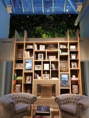 In back of boutique there are comfy chairs and a living wall above the bookcase.